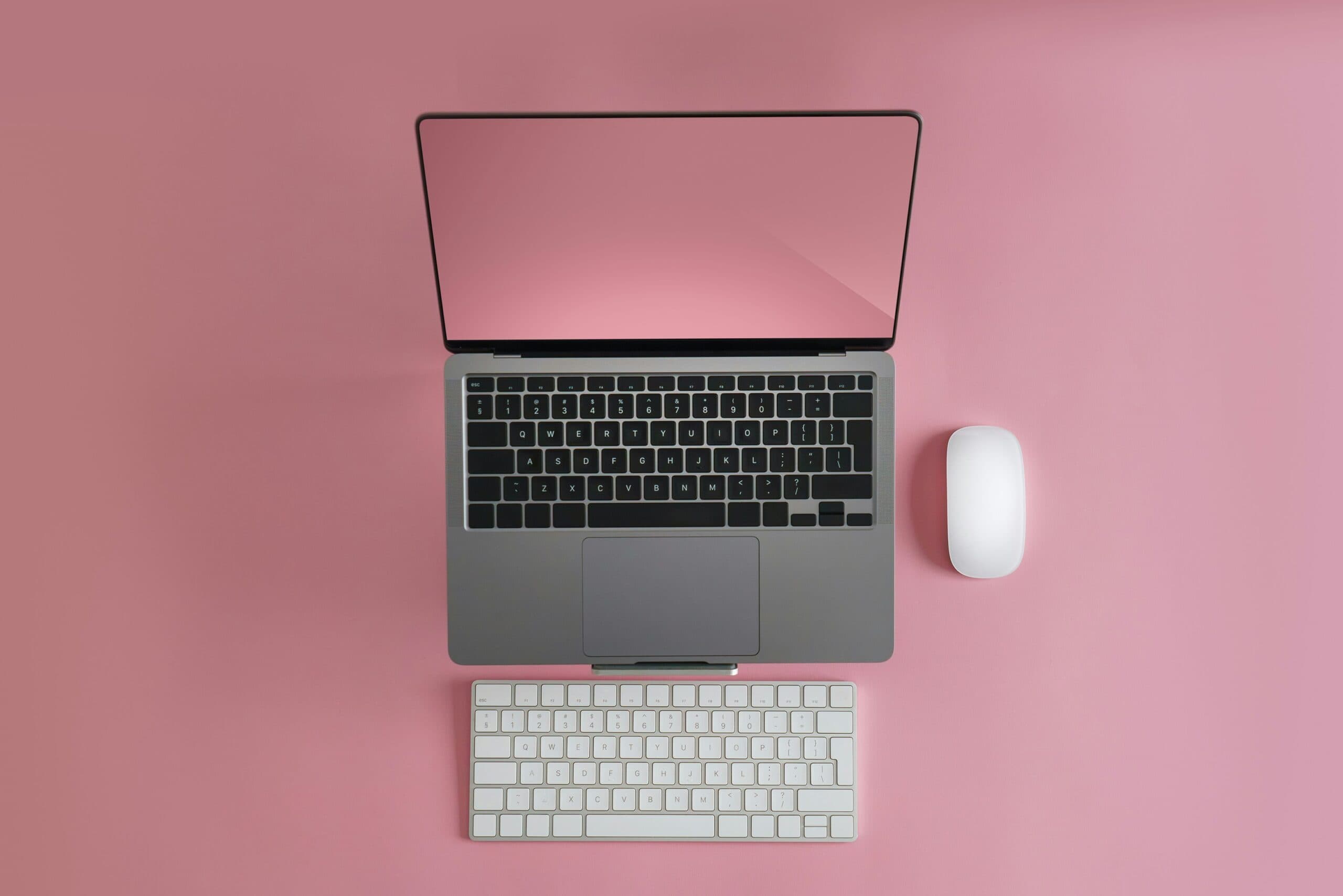 laptop with mouse and keyboard on solid pink background